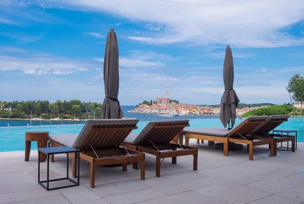 Four lounge chairs in front of the infinity pool with the city in the distance.