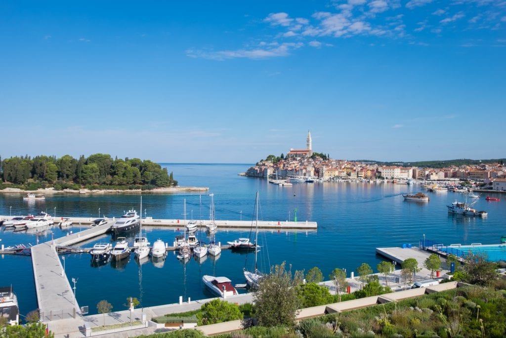 View from the hotel: the city skyline of Rovinj, and in front of it, a pier with several boats docked.