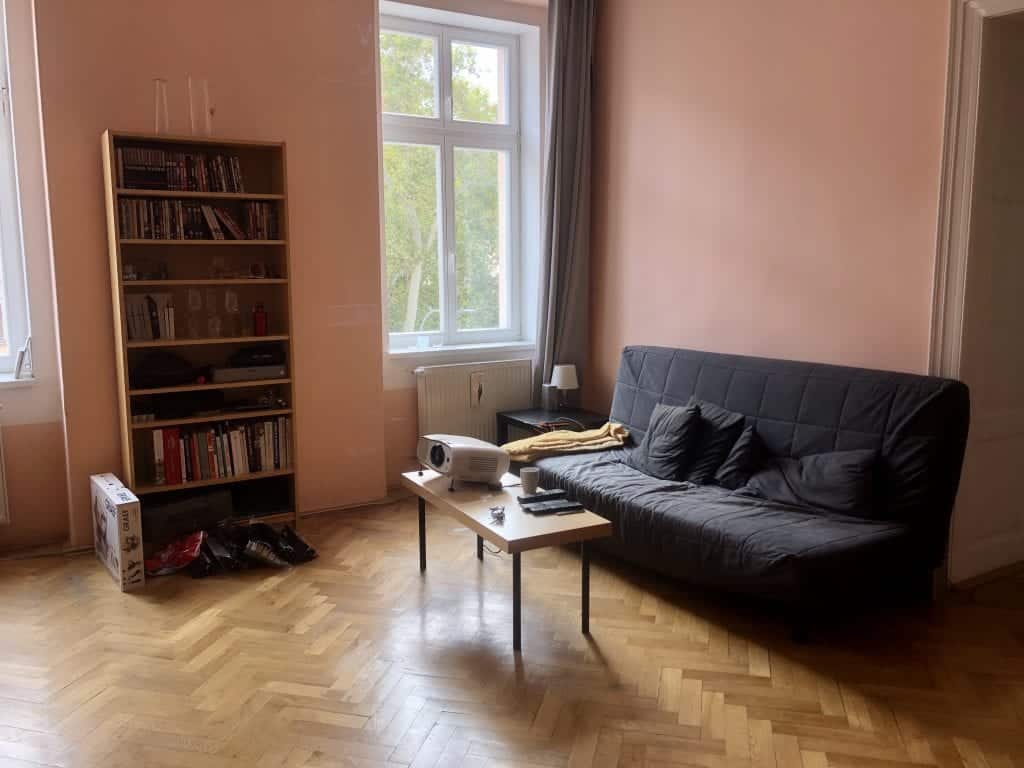 The old living room: tall wooden bookcase, wooden table with black plastic legs, and old gray futon.