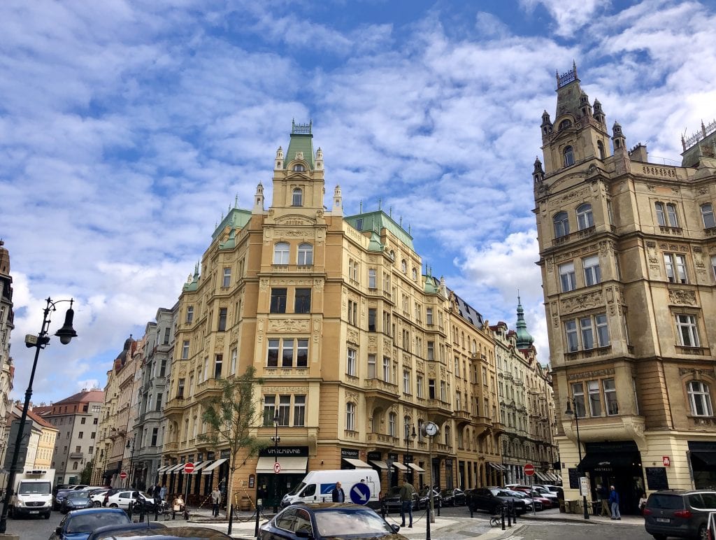 A yellow building with crenellation underneath a blue and white sky in Prague.