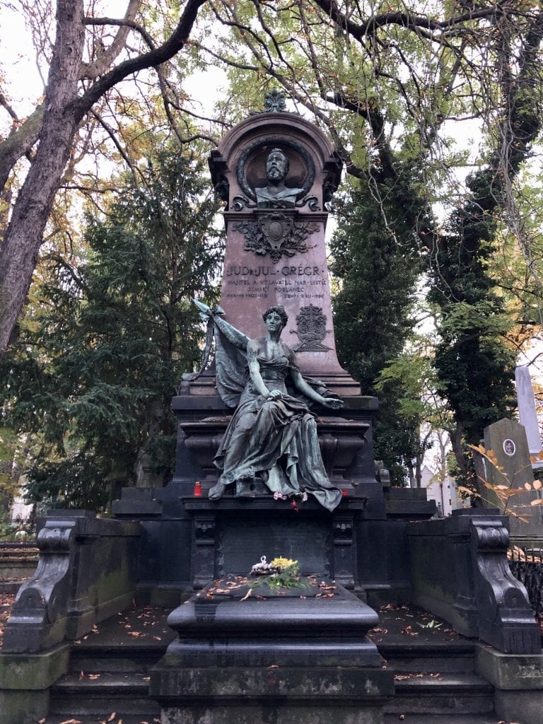 A giant gravestone featuring a man's head and a green angel statue.