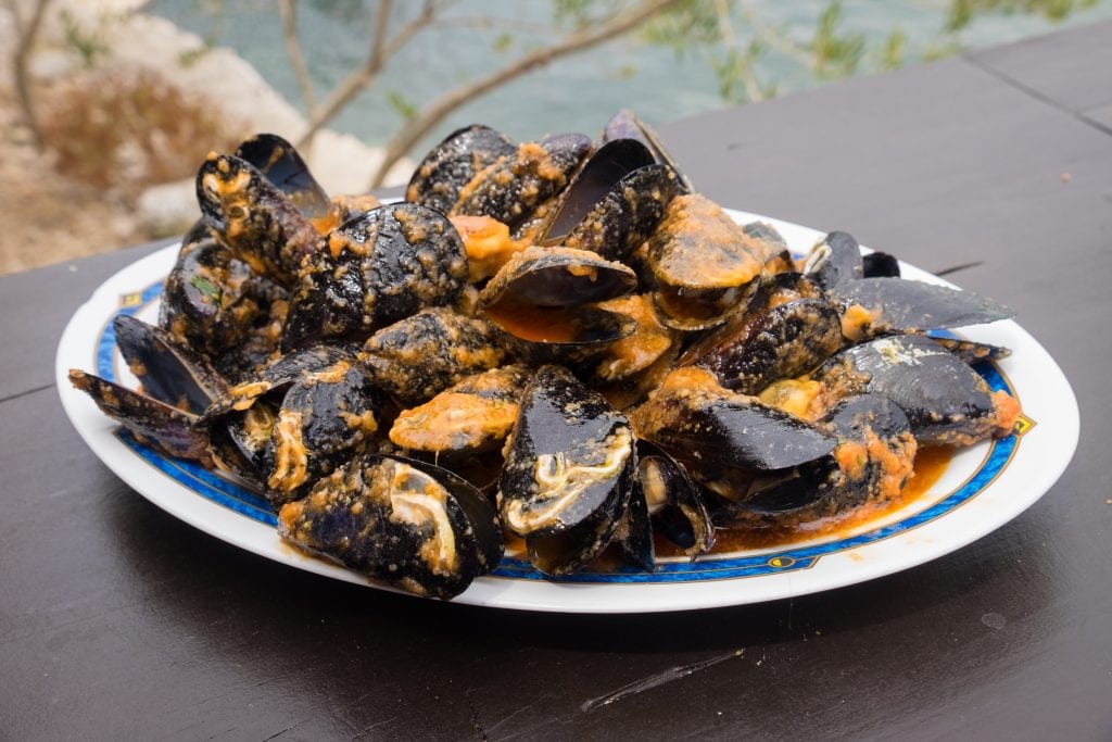 A big plate of mussels in a tomato-based sauce.