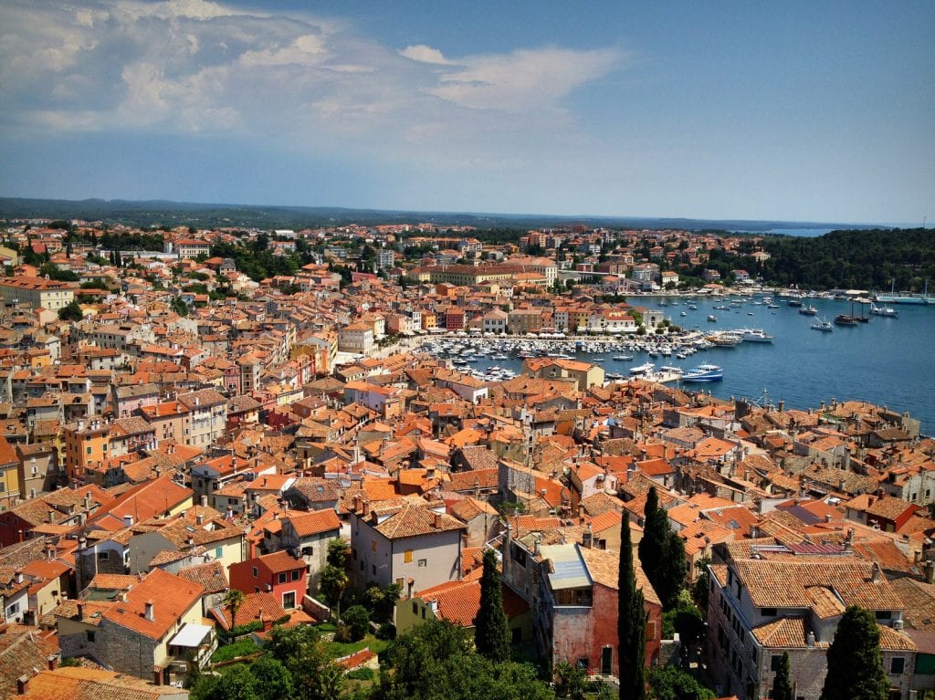 View from the top of the church in Rovinj -- layers and layers of orange terra cotta roofs, sloping down and leading to the bright blue sea.