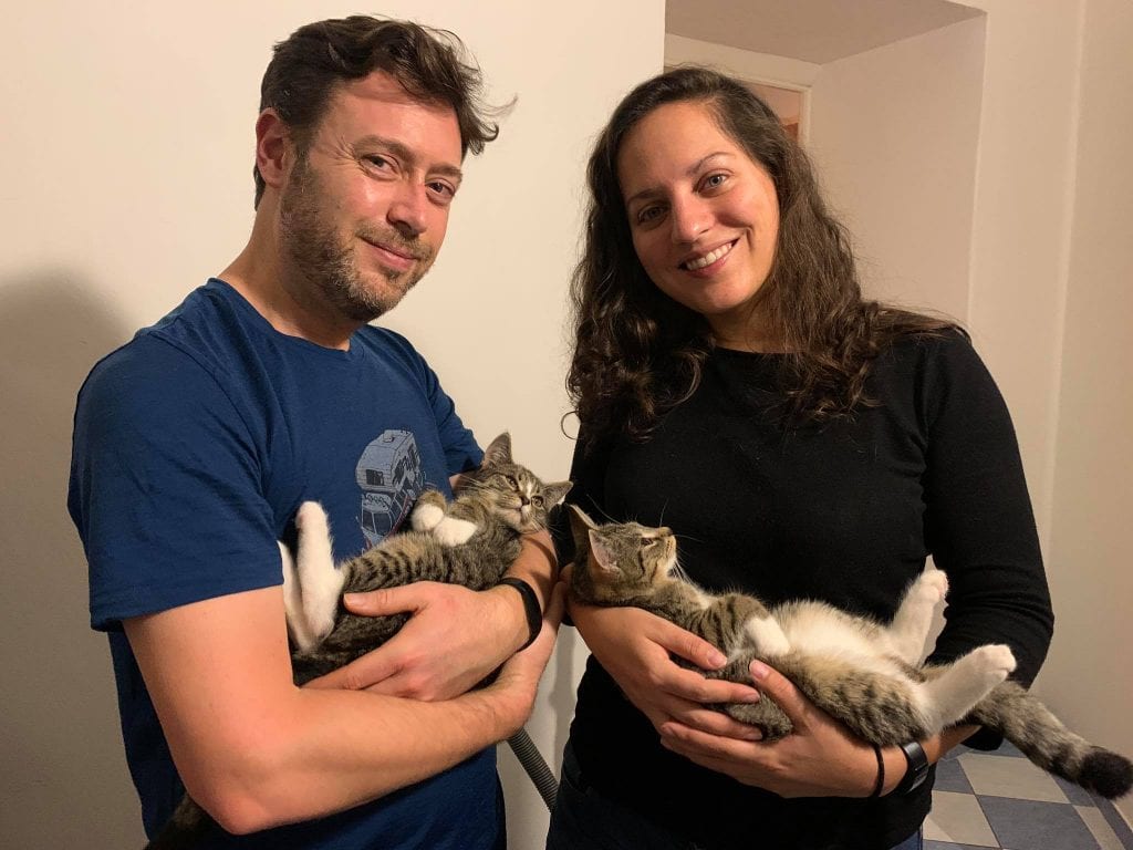 Charlie and Kate each holding a small gray tabby cat with white socks.