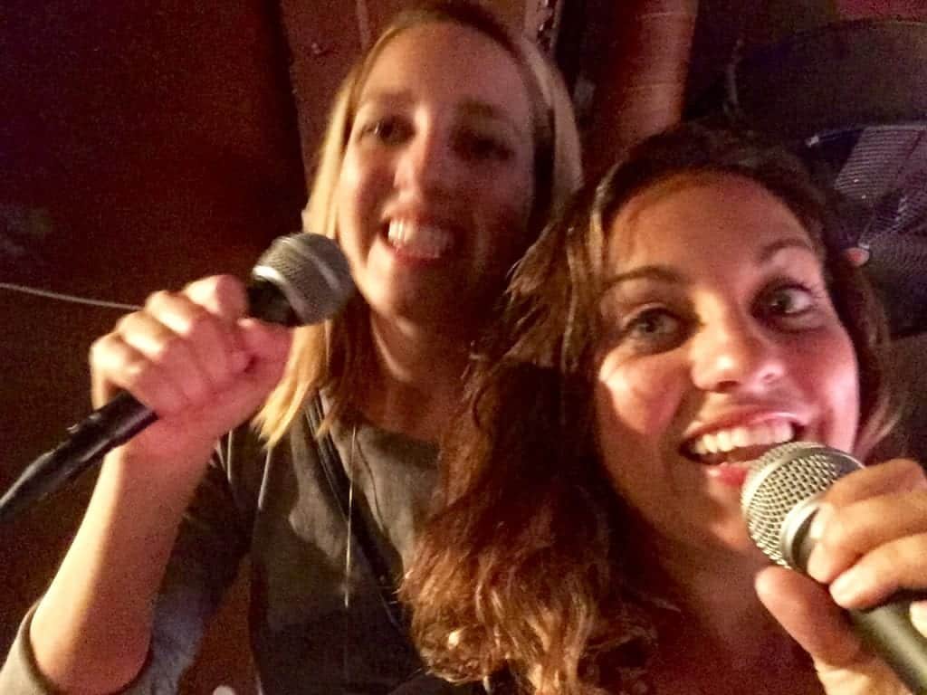 Kate and her sister Sarah singing karaoke into microphones together.