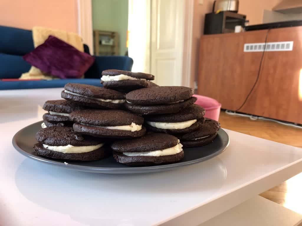 A pile of giant, delicious-looking homemade Oreos. They look a bit like Whoopi pies. Nearly black shortbread with buttercream oozing between each cookie.