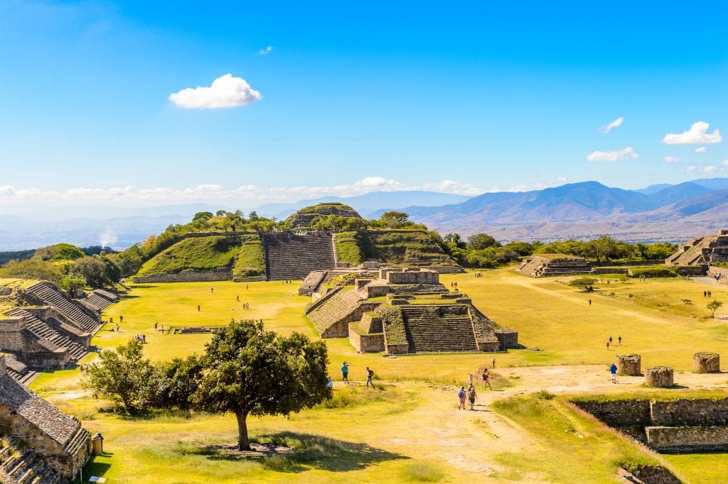 The Monte Alban ruins: several flap-topped stone pyramids, many of them topped with vegetation.