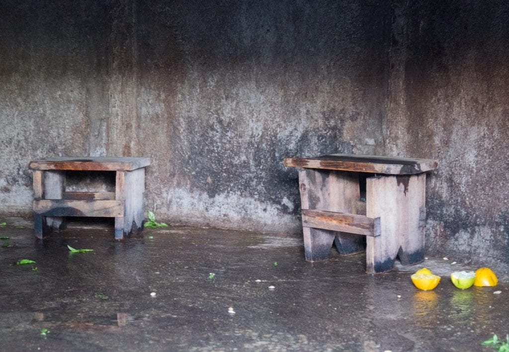 Two benches inside a cave-like setting, with discarded herbs and squeezed halves of oranges in the ground.