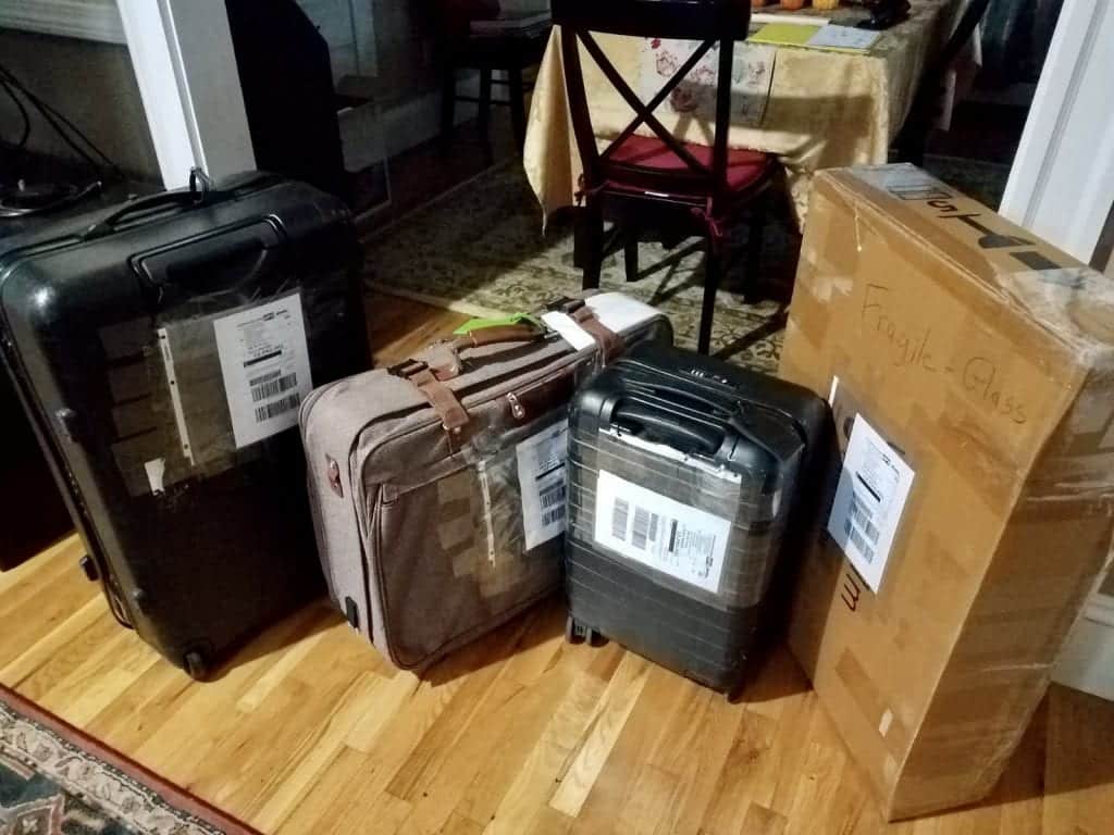 A pile of three suitcases and a large box, covered with shipping labels.