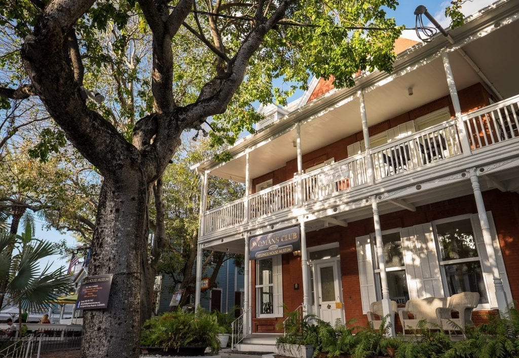 The Key West Women's Club, a red building with white wraparound porches. In front of it is a massive oak tree.