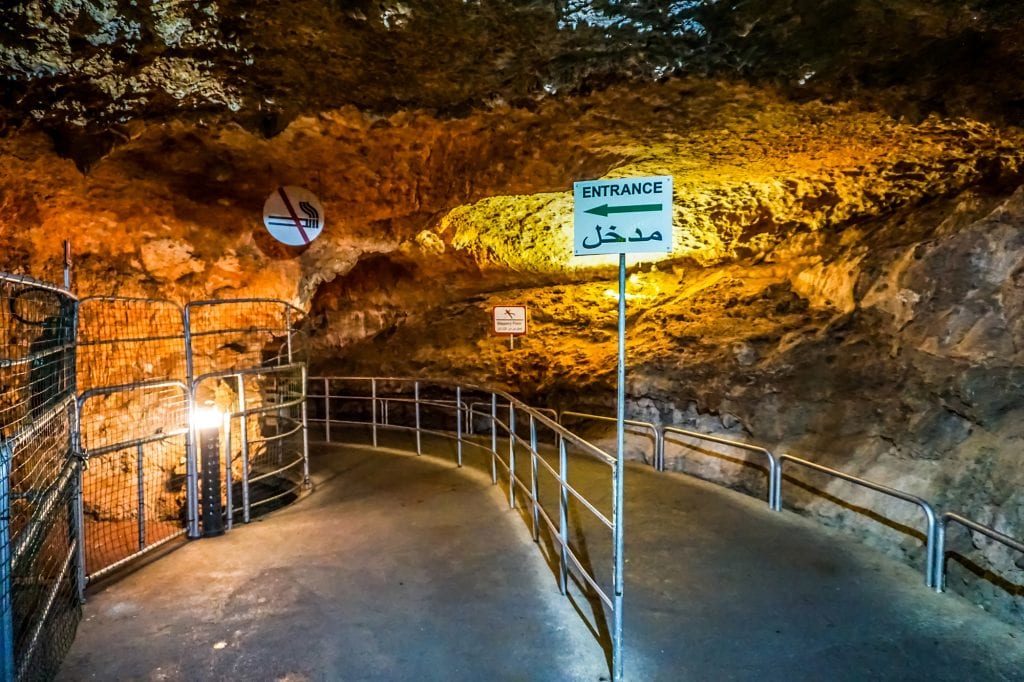 An entrance to Jeita Grotto -- you see metal dividers leading into a cave and a sign that says "Entrance" both in English and Arabic.