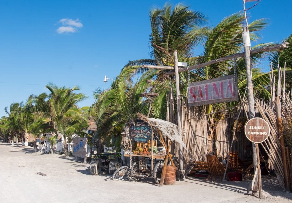 Beach shacks and bars beneath palm trees on the beach in Holbox, Mexico.