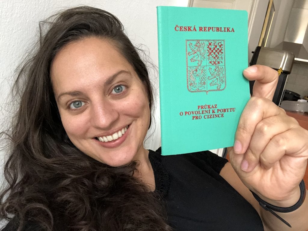 Kate smiles and holds up a minty green passport-like book with Czech writing on it in red -- her residency book.