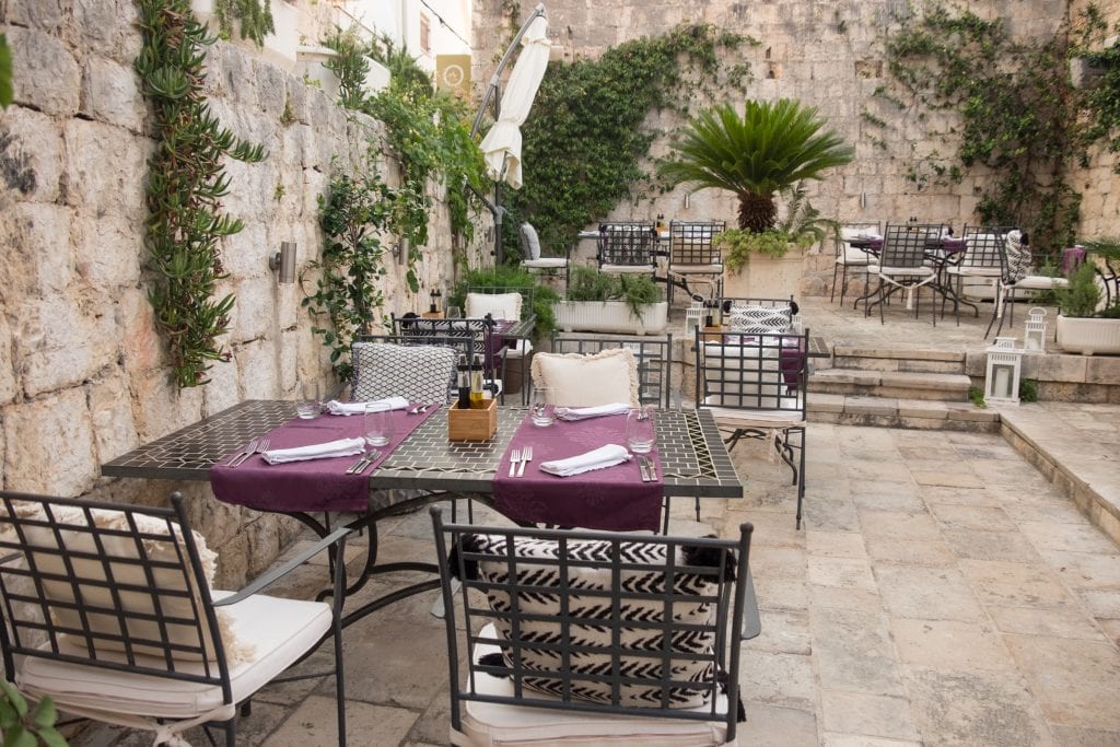 The outdoor dining room, wrought iron tables with purple placemats and chairs covered with black and white cushions filling the space.