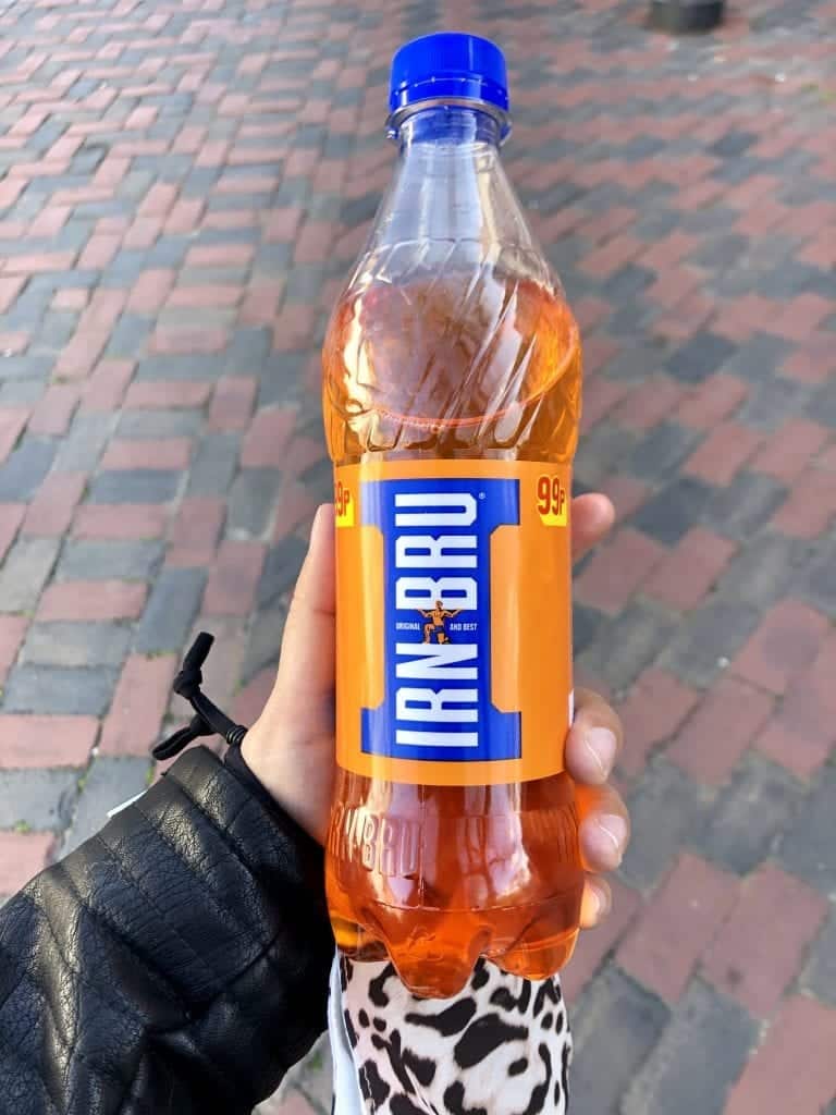 Kate holds a bottle of Iron Blu, a bright orange soda from Scotland.