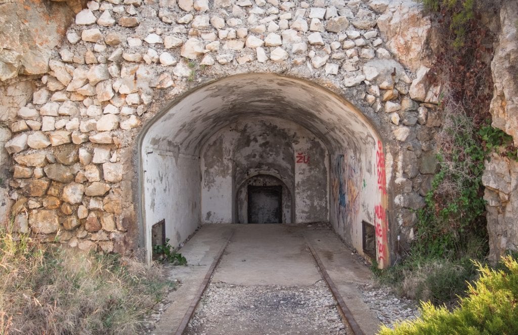 A military tunnel entrance, carved out of the mountain and covered with graffiti.