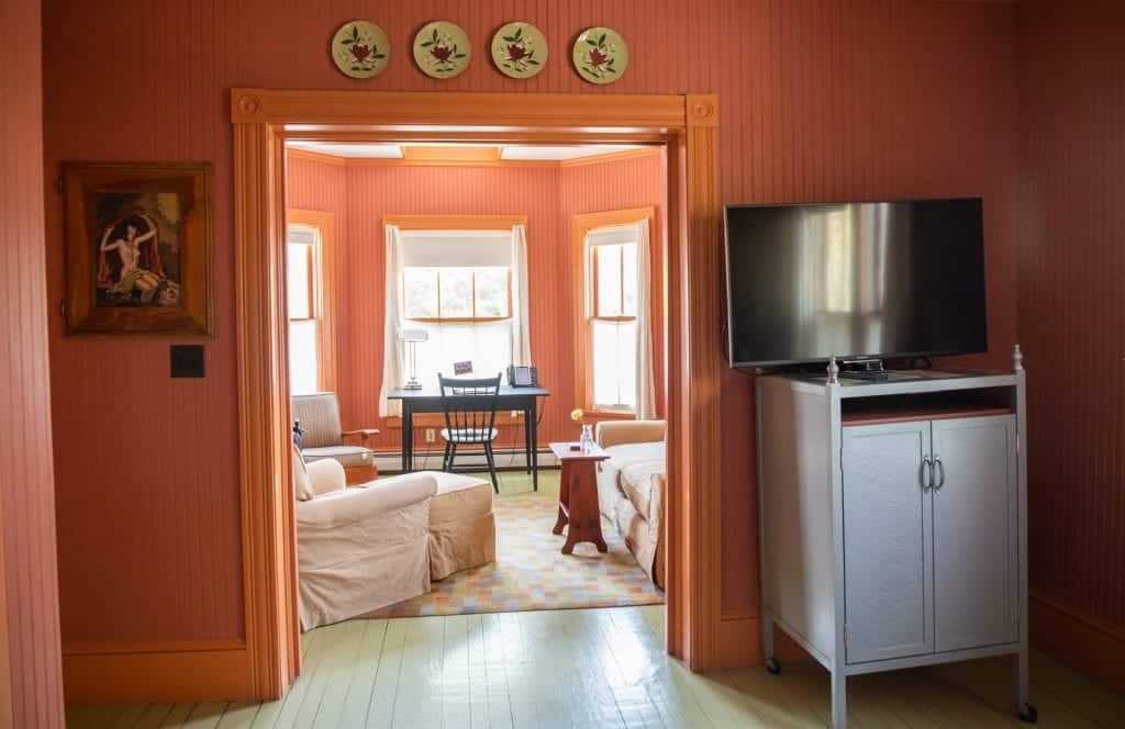 The room from the other angle: above the door frame four vintage plates are attached. You also see a desk and two chairs in the next room.