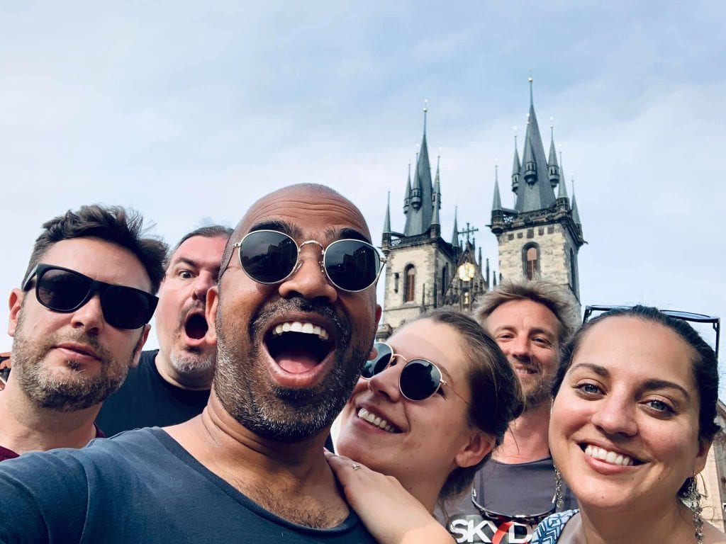 Kate and friends, including Kash, taking a selfie with big smiles as the spires of a Prague church peek through in the background.