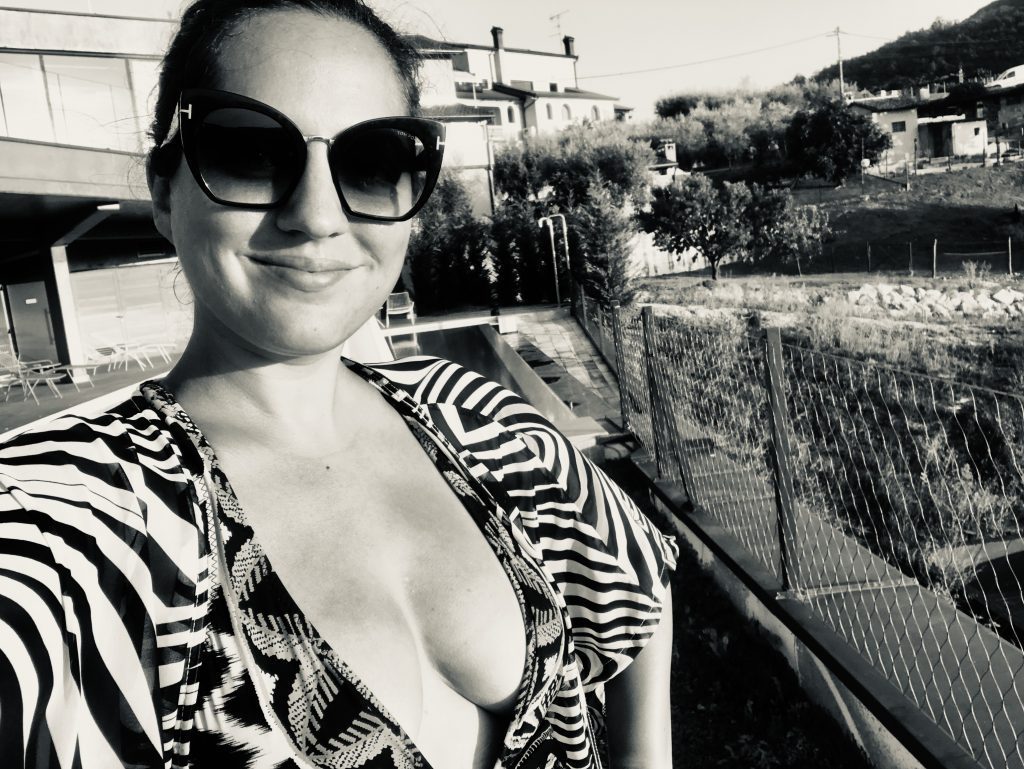 A Black and white shot of Kate in sunglasses, a low-cut bathing suit and a zebra-print kimono on top, with sunglasses.