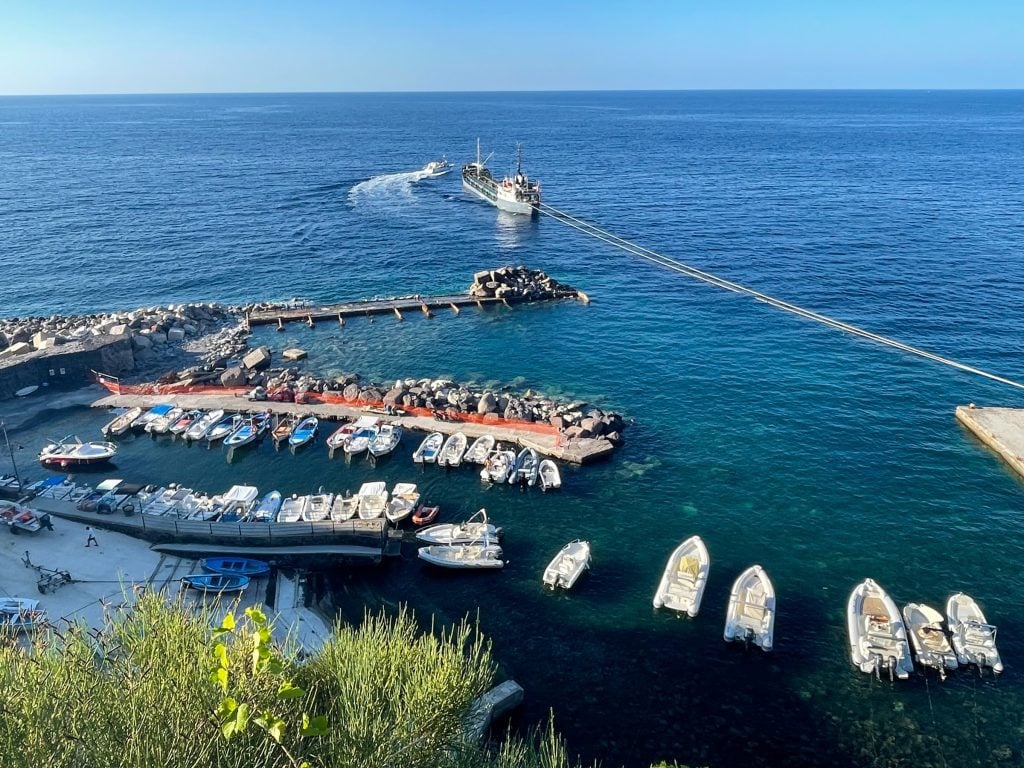 The port of Malfa, Salina, with dozens of small white boats lined up along makeshift concrete docks.