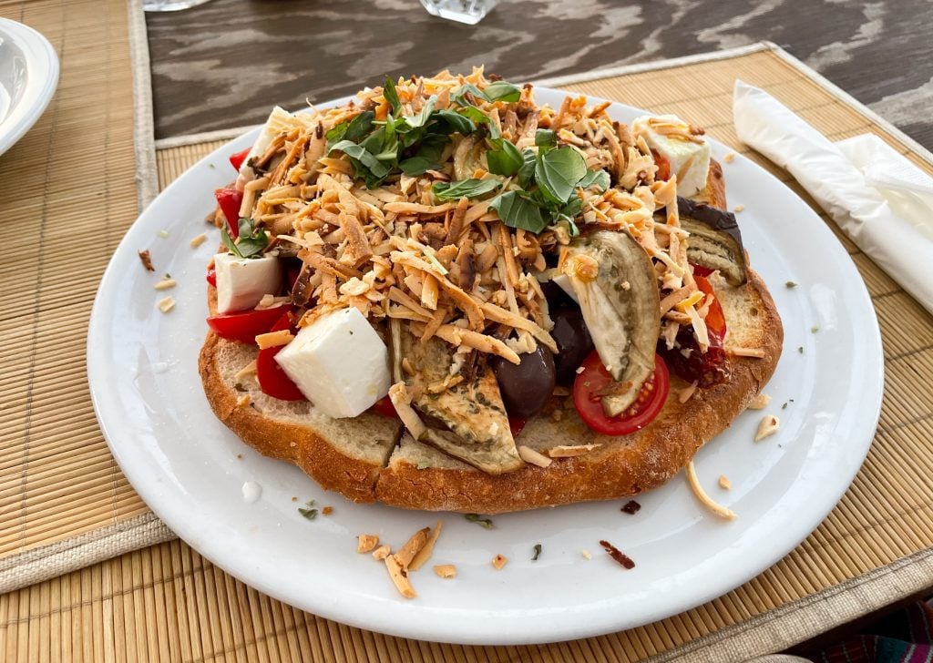 Pane Cunzato: a big piece of flatbread topped with tomatoes, mozzarella, marinated eggplant, capers, olives, shredded ricotta infornata cheese, and fresh herbs. Definitely enough for two people to eat.