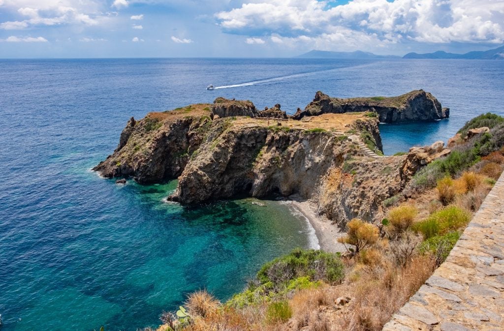 The peninsula of Panarea, jutting out from the mainland like a big pile of rocky earth, surrounded by bright blue-green clear water. It looks like a place in a Greek myth.