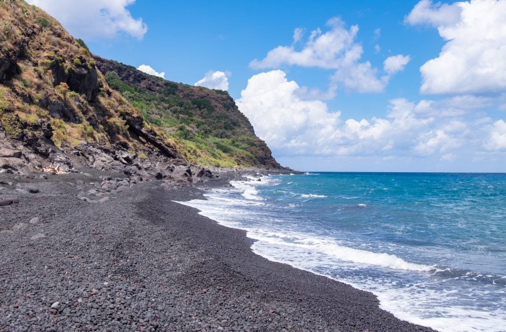 Beautiful Spiaggia Lunga, a sparkling black sand beach with bright blue waves, tall green cliffs in the distance. If I didn't know where this was taken I would guess Hawaii.