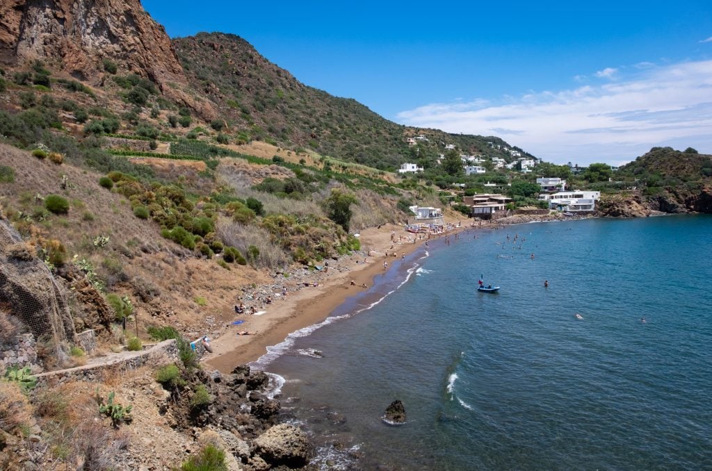 Spiaggia Zimmari, a long brown sandy beach with lots of kids and adults on it.