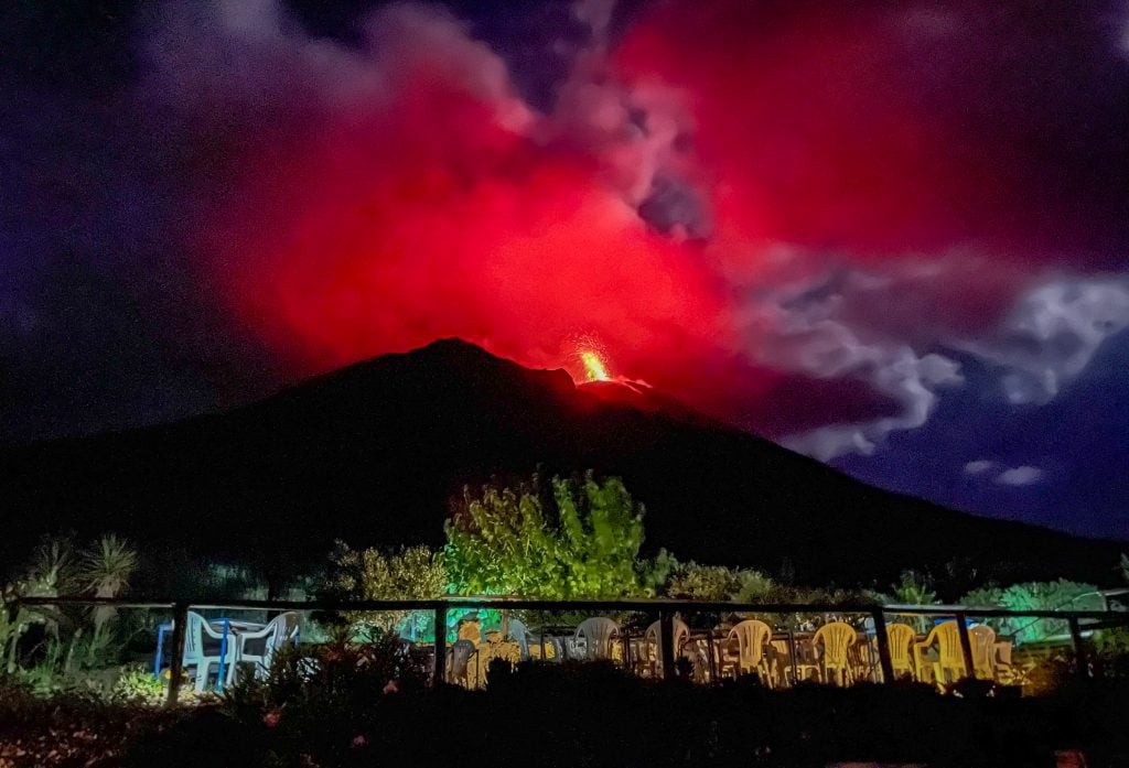 Stromboli's volcano as seen from Osservatorio, spewing out a plume of bright red lava against a dark indigo sky, looking even more ominous than before.