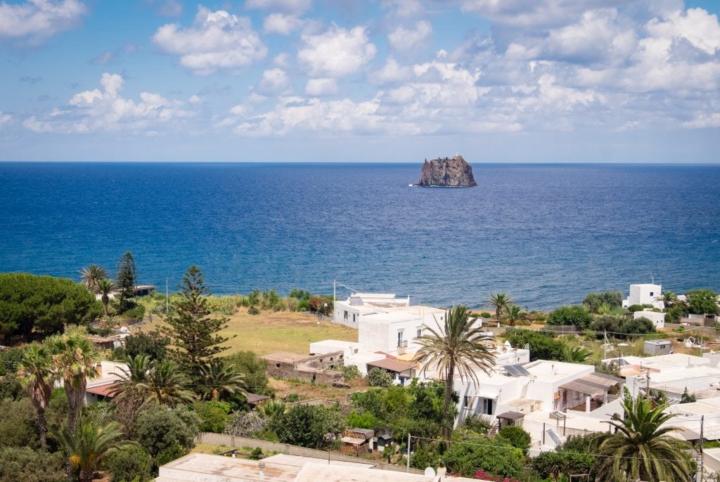 You see a tiny island, Strombolicchio, sticking straight out of the water in the distance, as seen from Stromboli.