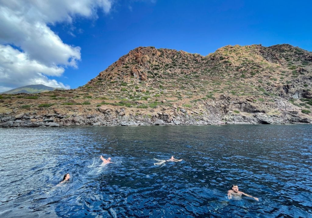 Four people swimming off the verdant coast of Filicudi.