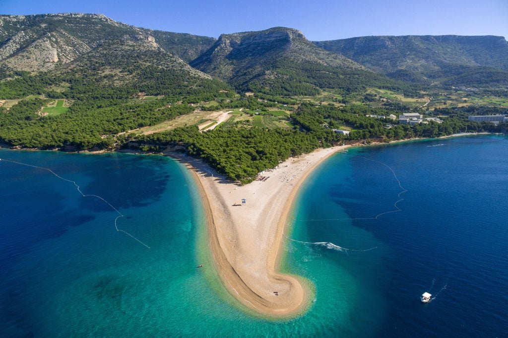 Zlatni Rat, the famous Golden Horn beach: A green forest island gives way to a long sandy horn-shaped beach, coming out from the island like a peninsula. It's not sandy in real life, it's all pebbles.