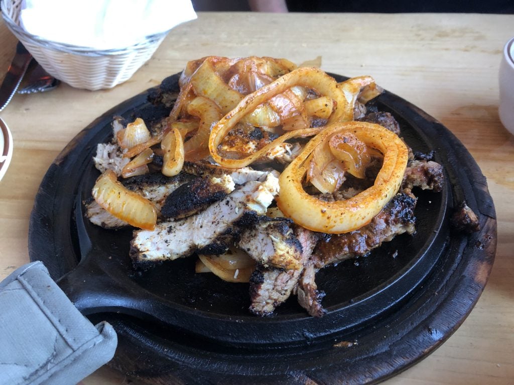 A plate of blackened chicken fajitas topped with onions.