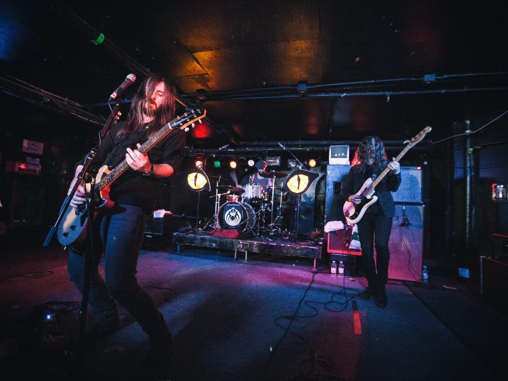 Two long-haired men playing guitars on stage.