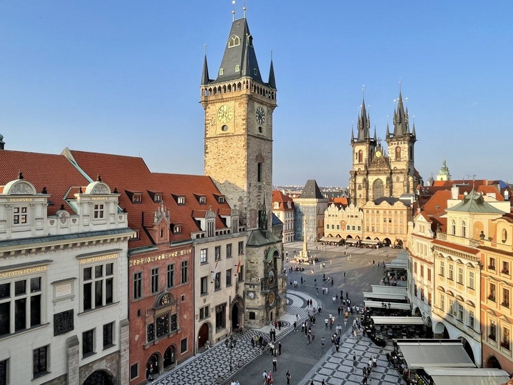 A view from above of Prague's Old Town Square, surrounded by castle towers and candy-colored houses.