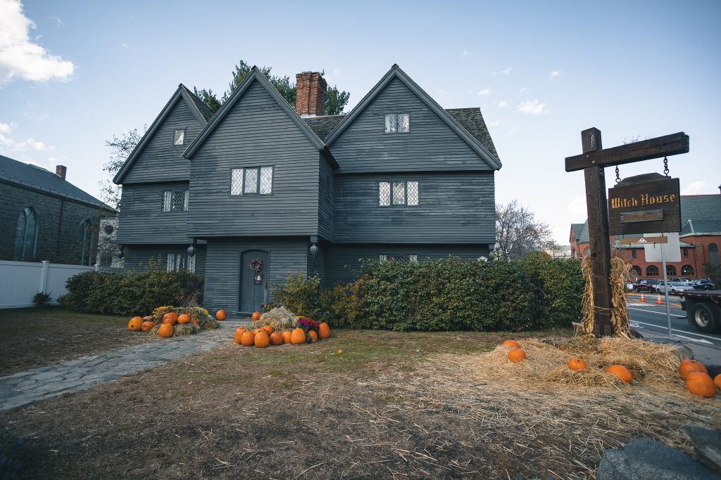 Another angle of the dark gray, small-windowed Witch House. In this photo it has displays of hay and pumpkins in front of the house.
