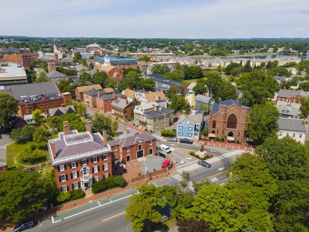 An aerial view of Salem, Massachusetts, historic red brick buildings interspersed with bright green trees.