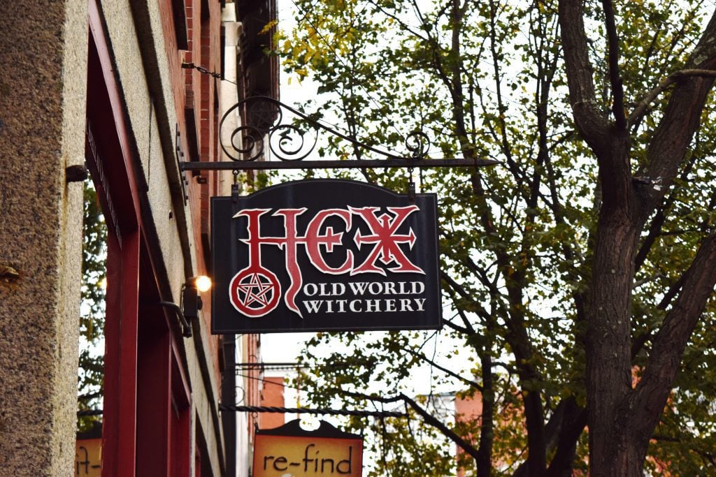 A sign outside a store reading Hex Old World Witchery with a pentagram on it.