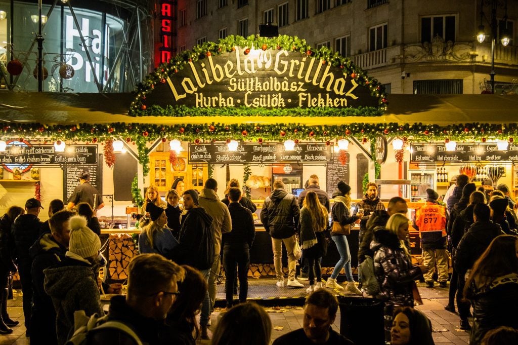 A large food stall selling beef goulash and stuffed cabbage, people lined up to buy.