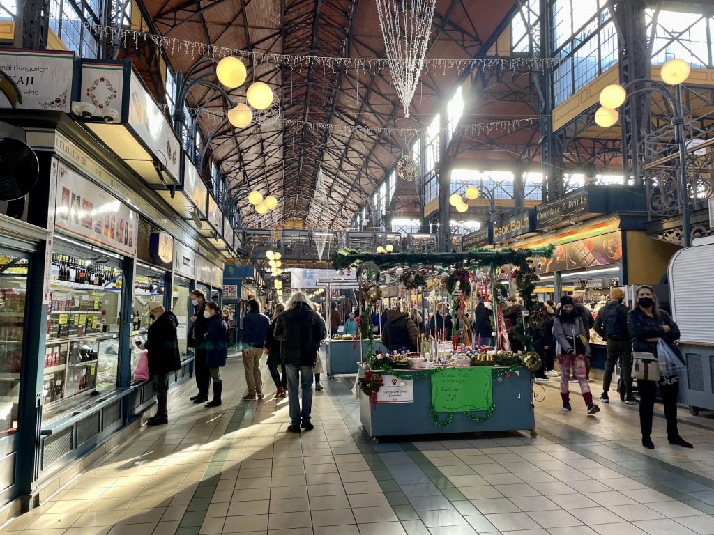 The giant old-fashioned market, with a very high ceiling, exposed metal beams, and Christmas lights dangling.