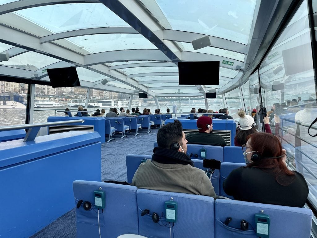 People sitting in a large, glass-enclosed covered boat.