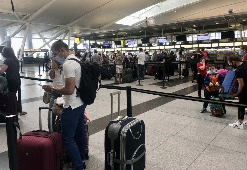 People lined up to check in at JFK airport, all wearing masks.