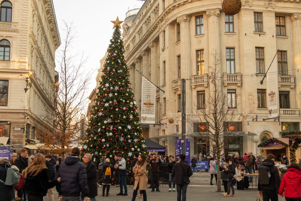 A tall Christmas tree covered with ornaments in front of stately buildings (and a Hard Rock Cafe) on Vorosmarty Square.