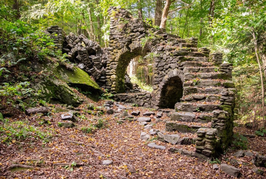 A falling-apart curved stone staircase standing on its own in the forest, literally nothing else around it.