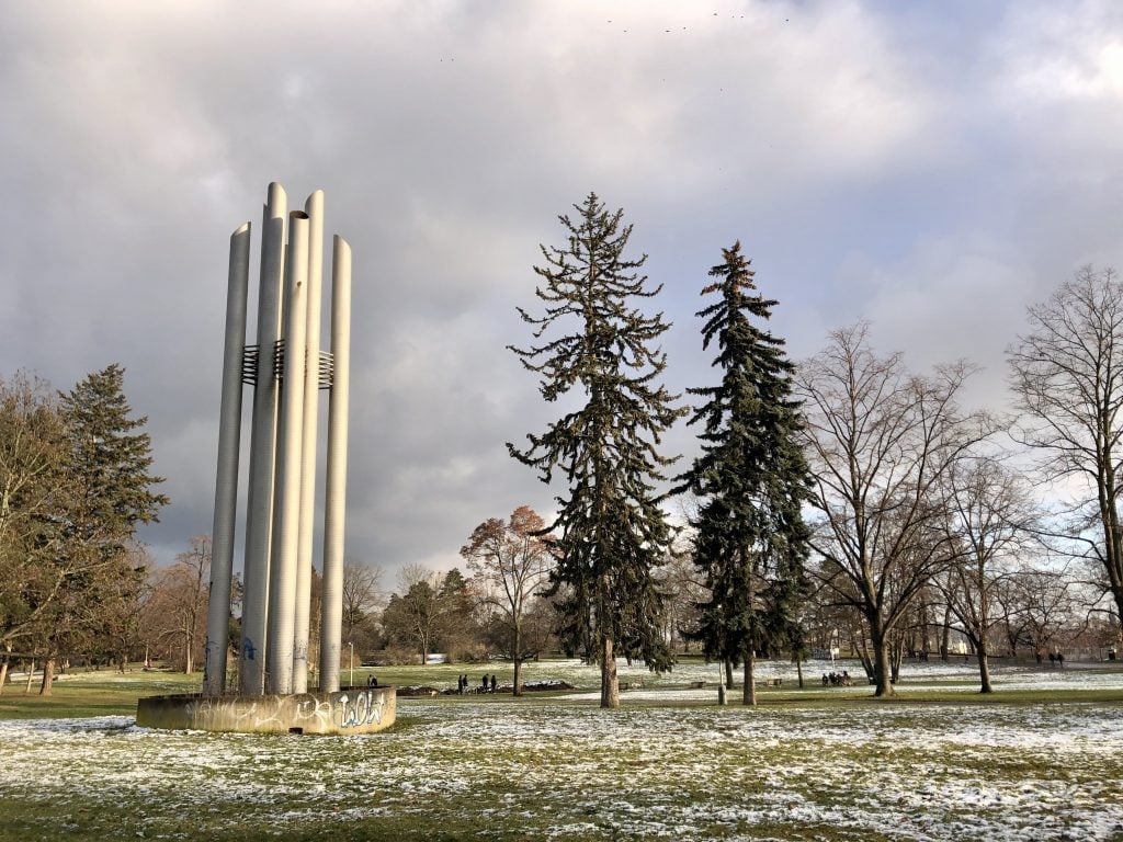 A park in Prague with the lightest dusting of snow on the ground, the grass peeking through in patches.