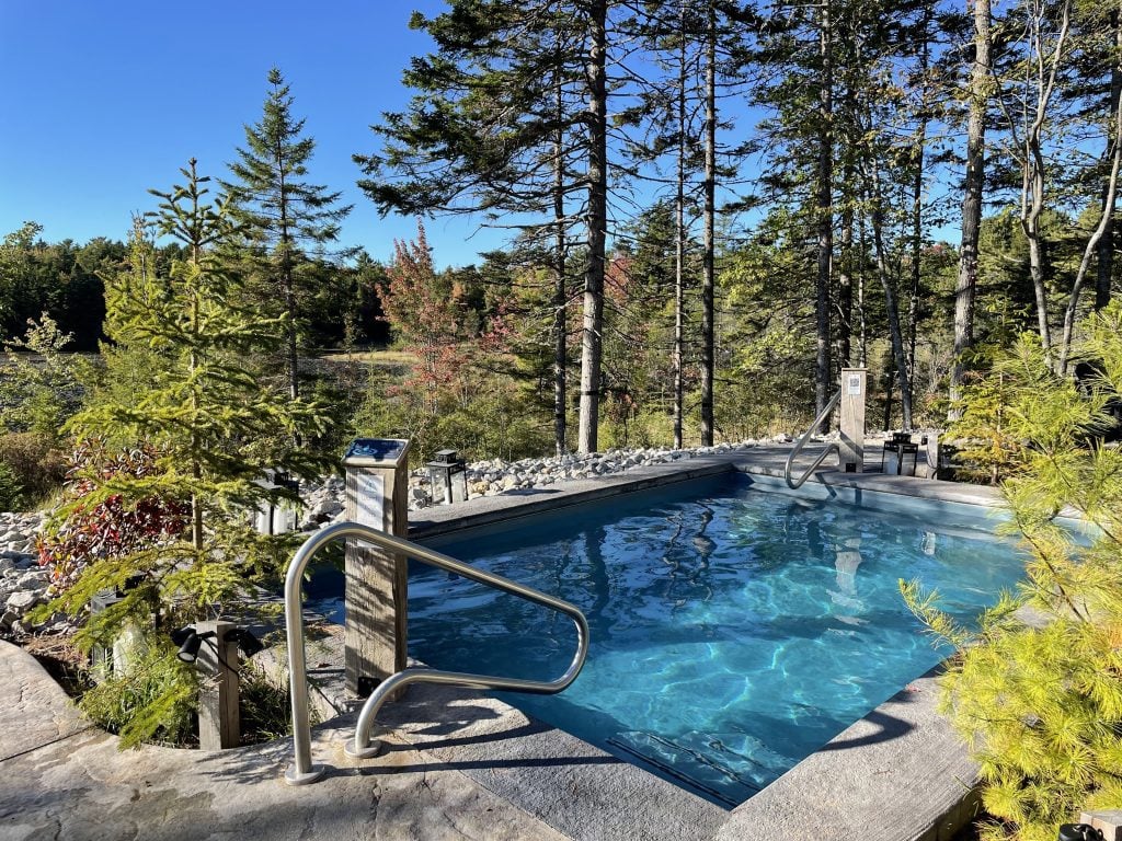 What looks like a blue swimming pool set among pine trees in a forest; it's actually a hot pool at Sensea Spa in Nova Scotia.