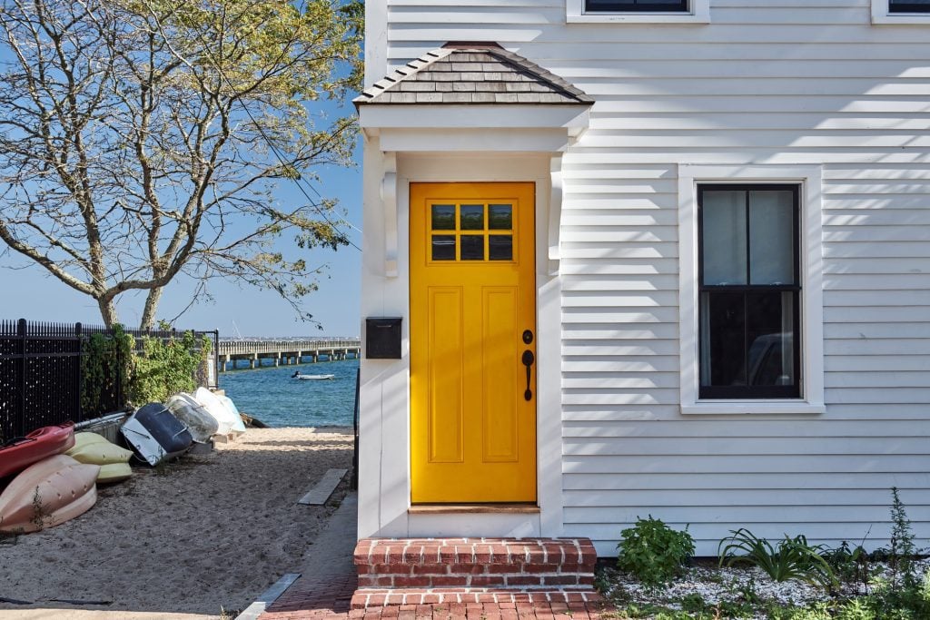 A white Provincetown home with a cheery yellow door.