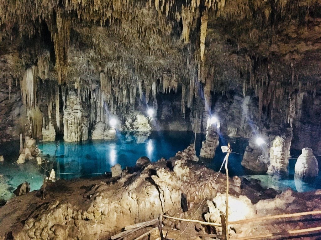 A very dark cenote inside a cave with lots and lots of large stalactites.