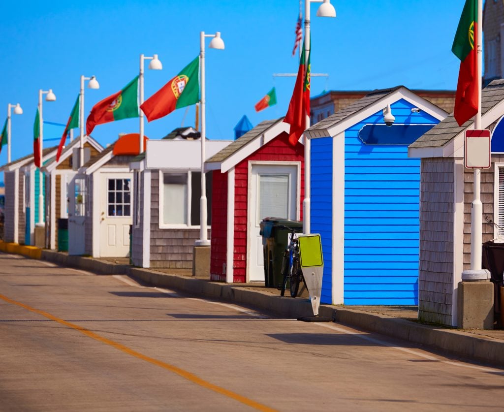 Brightly colored wooden cottages on MacMillan Pier, Portuguese flags flying behind.