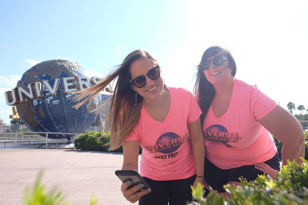 Kate and her friend Cailin, wearing matching pink shirts in front of the giant globe reading Universal Studios.